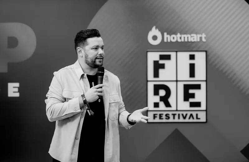 Juvenal Valentim falando ao microfone no palco do Hotmart FIRE Festival