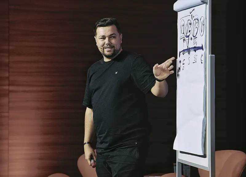 Juvenal de pé ao lado de um flip chart, explicando um esquema desenhado à mão